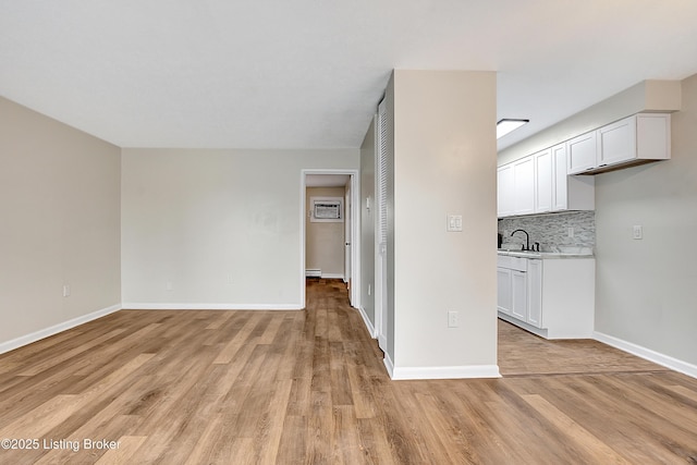 interior space with tasteful backsplash, light countertops, open floor plan, white cabinets, and a sink