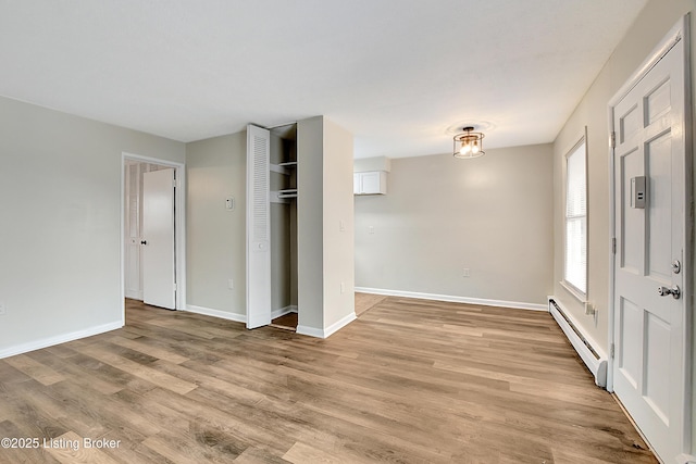 foyer entrance with a baseboard heating unit, light wood-type flooring, and baseboards