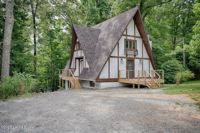 view of front facade with a forest view, a shingled roof, and stucco siding