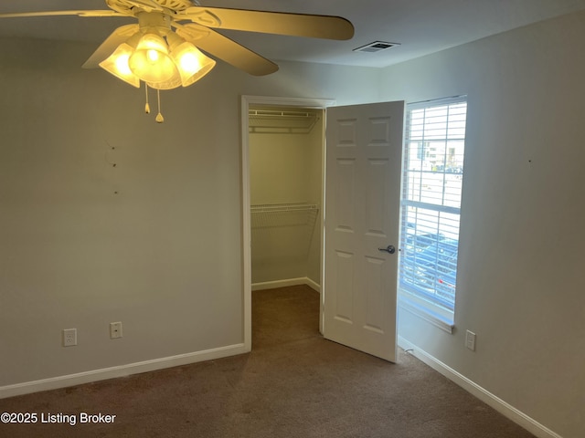 interior space featuring carpet floors, baseboards, visible vents, and a ceiling fan