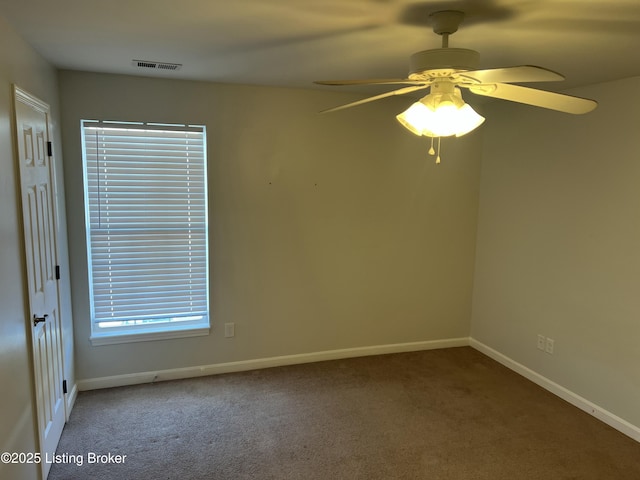 carpeted empty room featuring a ceiling fan, visible vents, and baseboards