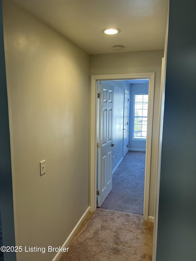 hallway featuring carpet flooring and baseboards