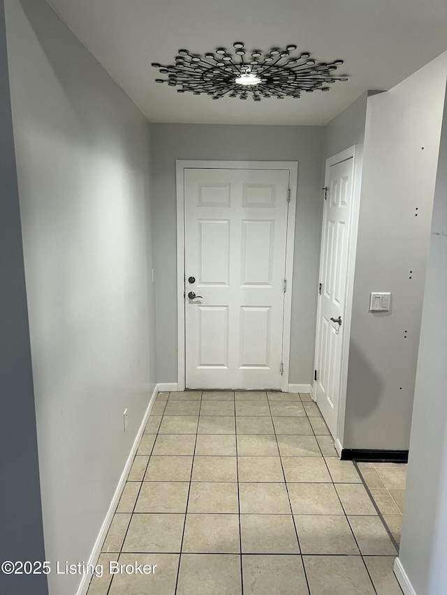 hallway featuring baseboards and light tile patterned flooring