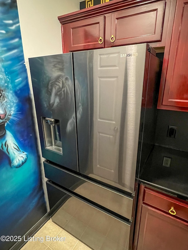 kitchen with dark countertops, tile patterned floors, reddish brown cabinets, and stainless steel fridge with ice dispenser