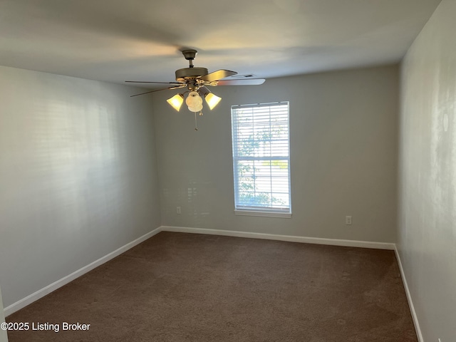 empty room with ceiling fan, dark colored carpet, and baseboards