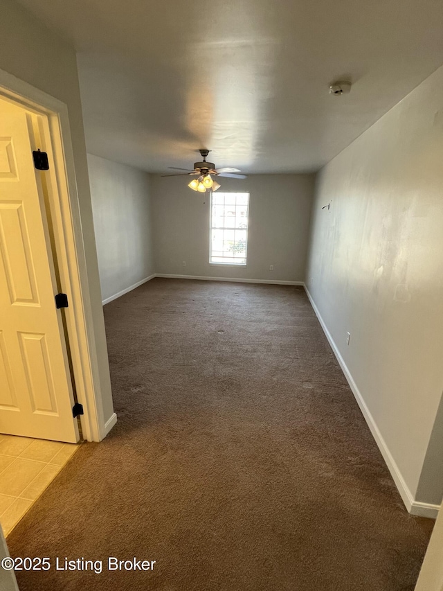 tiled empty room featuring carpet floors, a ceiling fan, and baseboards