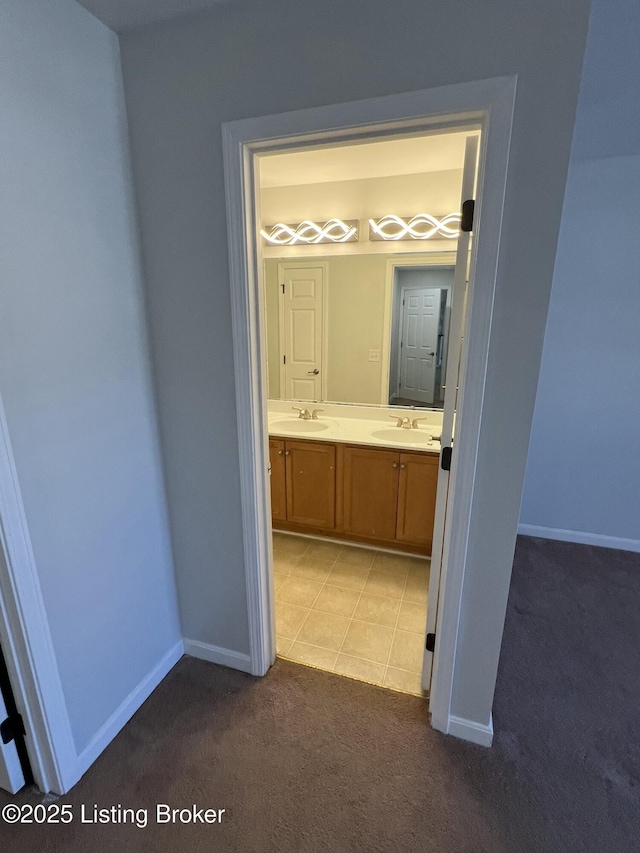 corridor with light carpet, a sink, and baseboards