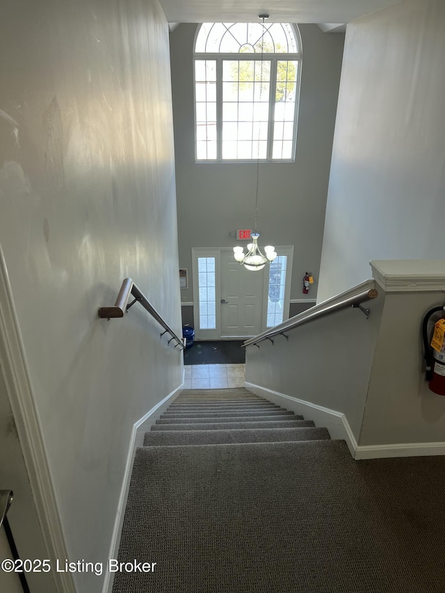 stairs with a wealth of natural light, a towering ceiling, and baseboards