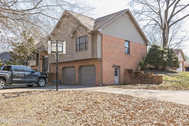 view of side of home featuring a garage, concrete driveway, and brick siding