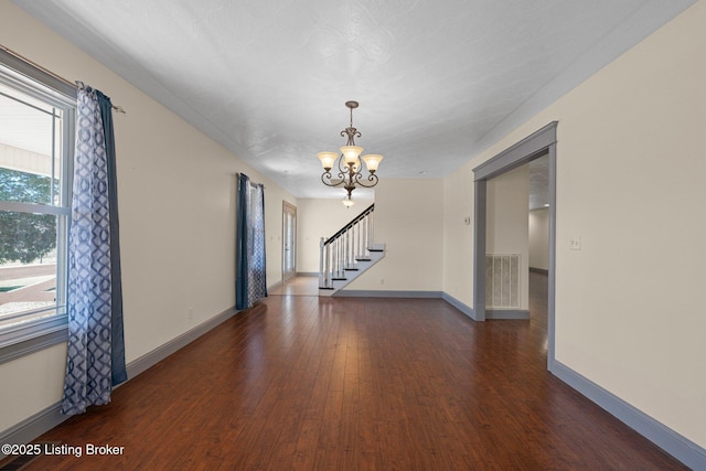 unfurnished room with baseboards, visible vents, wood finished floors, stairs, and a chandelier