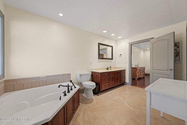 bathroom featuring recessed lighting, vanity, toilet, and a bath