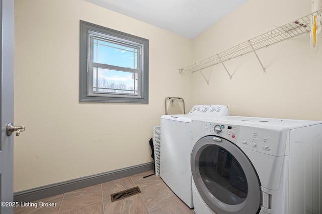 laundry area with laundry area, washing machine and dryer, visible vents, and baseboards