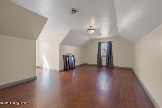 bonus room with lofted ceiling, dark wood-style flooring, visible vents, and baseboards