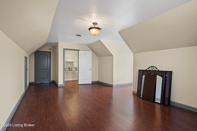 additional living space with lofted ceiling, visible vents, baseboards, and hardwood / wood-style flooring