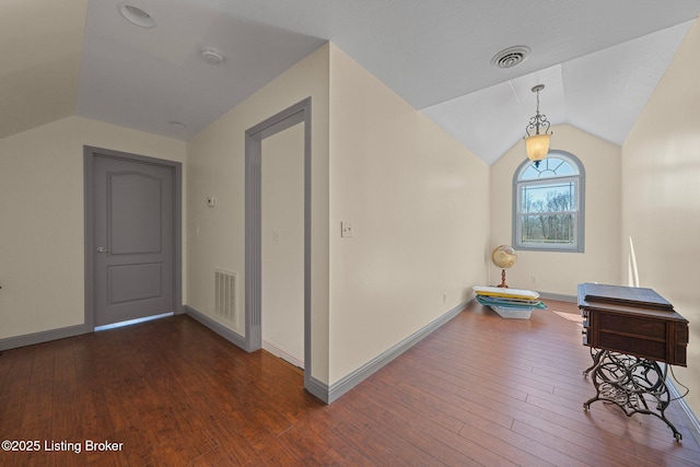 interior space featuring lofted ceiling, visible vents, baseboards, and hardwood / wood-style flooring