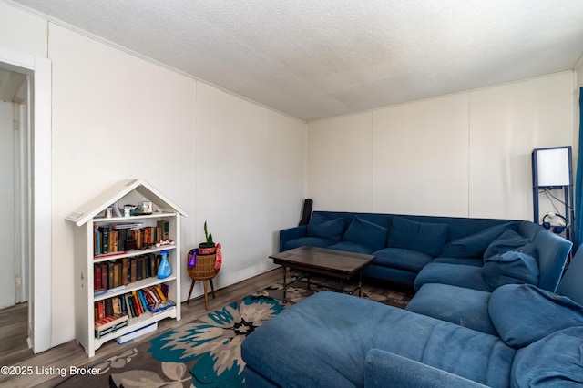 living area with a textured ceiling, a decorative wall, and wood finished floors