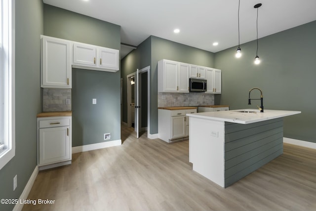 kitchen with white cabinetry, stainless steel microwave, and decorative light fixtures