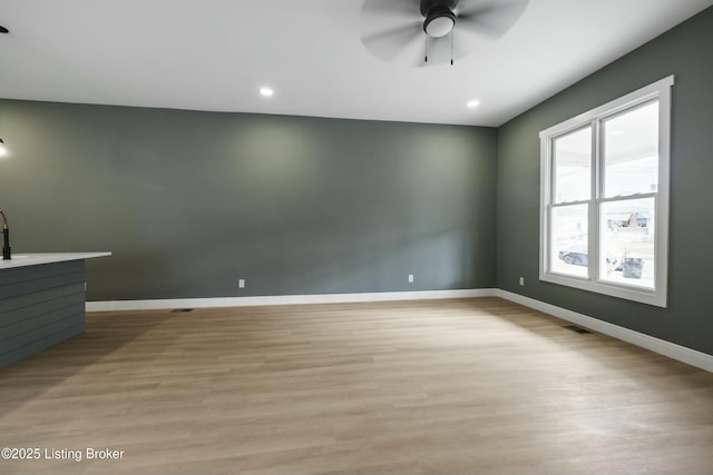 empty room with light wood-style flooring, visible vents, baseboards, and a ceiling fan