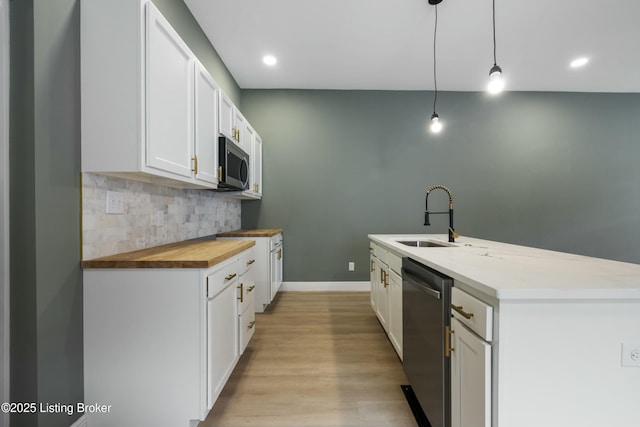 kitchen featuring a sink, white cabinets, wooden counters, appliances with stainless steel finishes, and tasteful backsplash