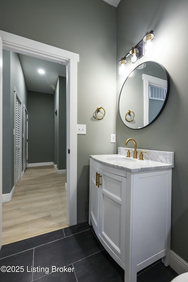 bathroom featuring baseboards, wood finished floors, and vanity