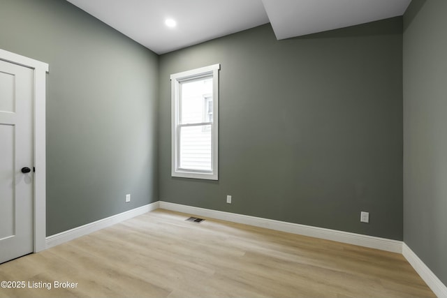 unfurnished room with light wood-type flooring, visible vents, and baseboards