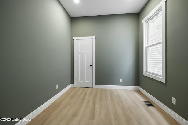 empty room featuring light wood-type flooring, visible vents, and baseboards