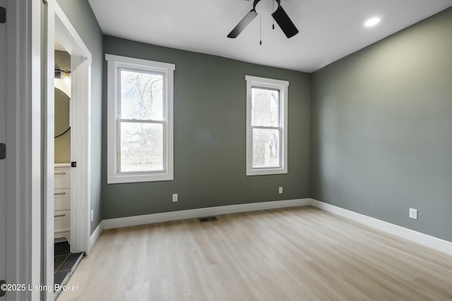 unfurnished bedroom featuring light wood-style flooring, ensuite bath, visible vents, and baseboards