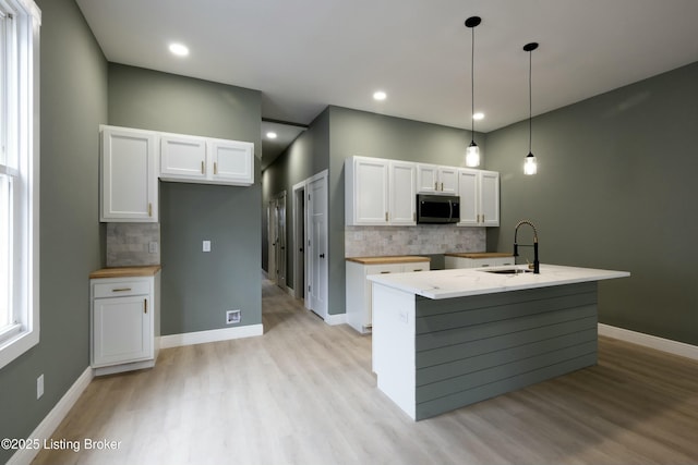 kitchen featuring light wood-type flooring, white cabinets, and stainless steel microwave