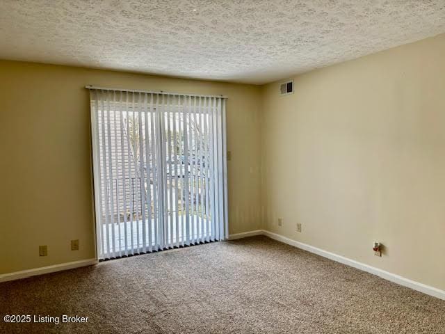 carpeted spare room with a textured ceiling, visible vents, and baseboards