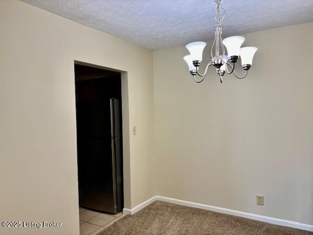 spare room with a chandelier, light tile patterned floors, a textured ceiling, light carpet, and baseboards