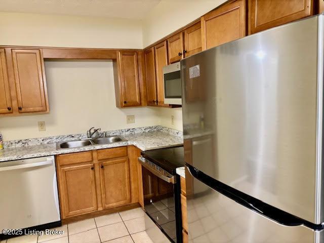 1515 La Fontenay Ct, Louisville, KY 40223 - kitchen featuring appliances with stainless steel finishes, brown cabinetry, a sink, and light tile patterned floors