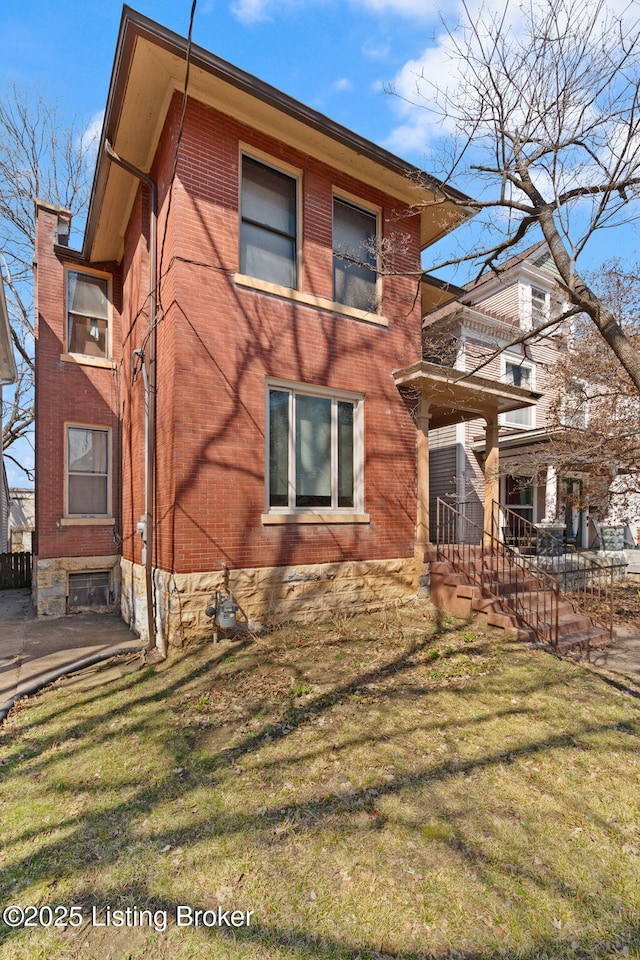 view of home's exterior with brick siding and a yard