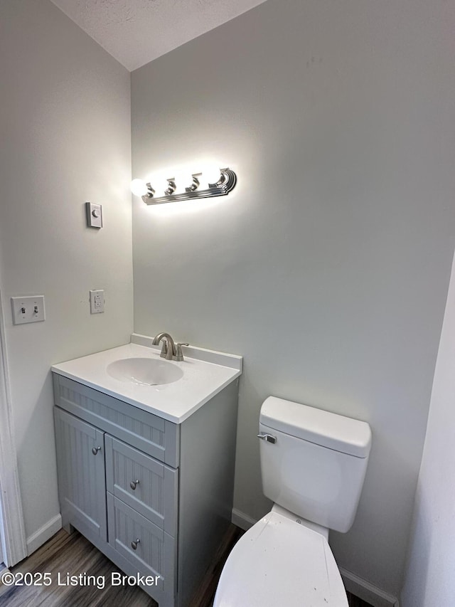 bathroom with baseboards, vanity, toilet, and wood finished floors