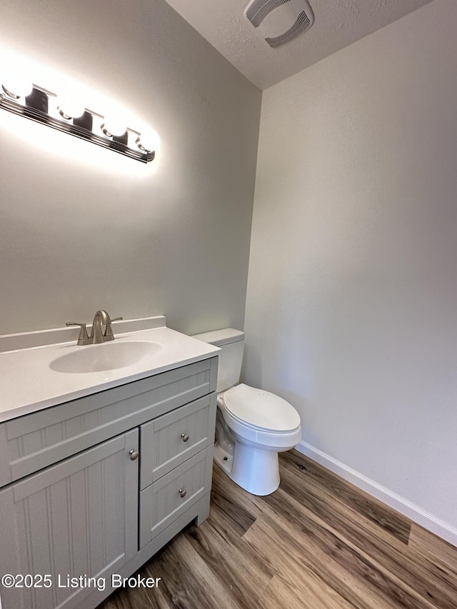 bathroom featuring visible vents, toilet, wood finished floors, a textured ceiling, and vanity
