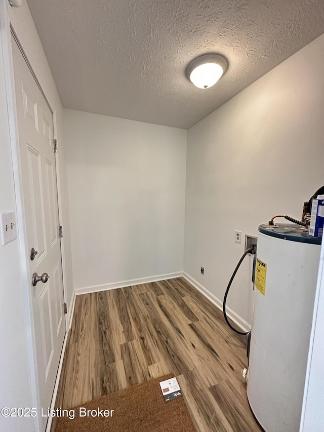 interior space with water heater, a textured ceiling, baseboards, and wood finished floors