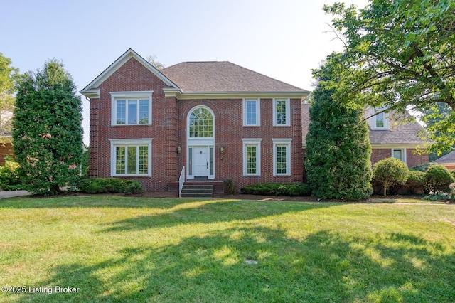 view of front of house with brick siding, a front yard, and a shingled roof