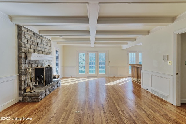 unfurnished living room with beam ceiling, a fireplace, french doors, and wood finished floors