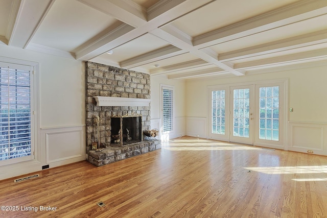 unfurnished living room featuring beam ceiling, wainscoting, a fireplace, and wood finished floors