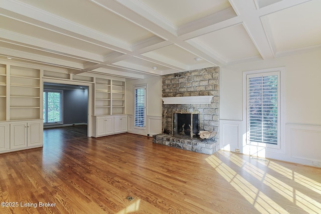 unfurnished living room with built in shelves, a fireplace, beam ceiling, and wood finished floors