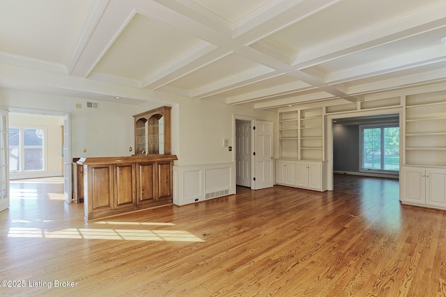 spare room featuring light wood finished floors, plenty of natural light, built in shelves, and beamed ceiling