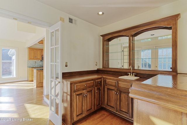 bar with recessed lighting, a sink, visible vents, light wood finished floors, and tasteful backsplash