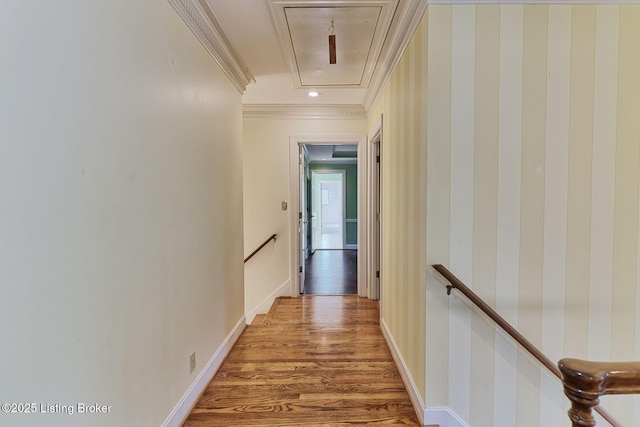 corridor with wood finished floors, an upstairs landing, baseboards, attic access, and crown molding