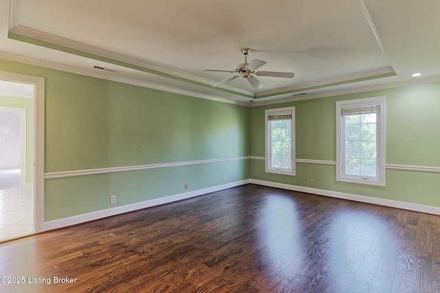 spare room featuring ornamental molding, a tray ceiling, baseboards, and wood finished floors