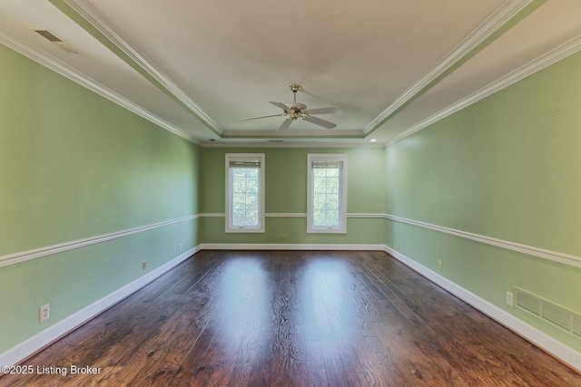 empty room with baseboards, visible vents, a tray ceiling, and wood finished floors