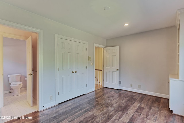 unfurnished bedroom with recessed lighting, a closet, connected bathroom, wood finished floors, and baseboards