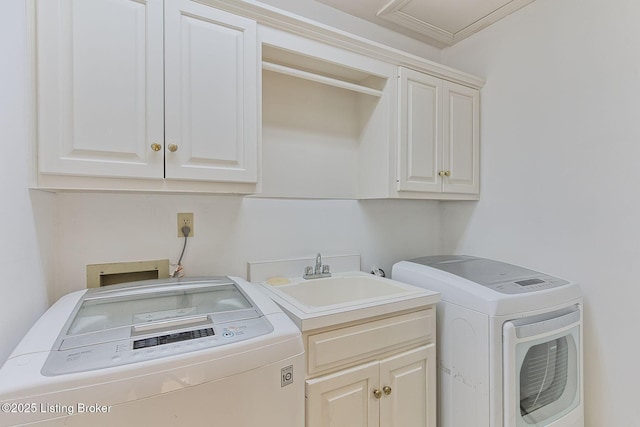 clothes washing area featuring cabinet space, a sink, and washer and clothes dryer