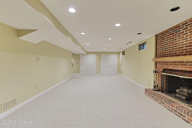 unfurnished living room featuring recessed lighting, light colored carpet, visible vents, a brick fireplace, and baseboards