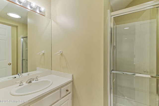 bathroom featuring a shower with door and vanity