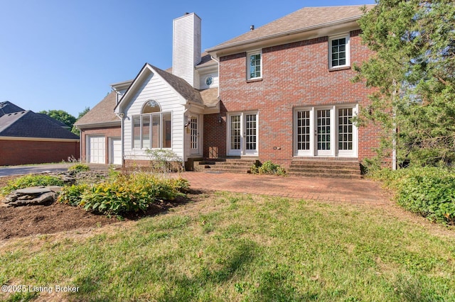 rear view of house with brick siding, a chimney, a lawn, entry steps, and a garage