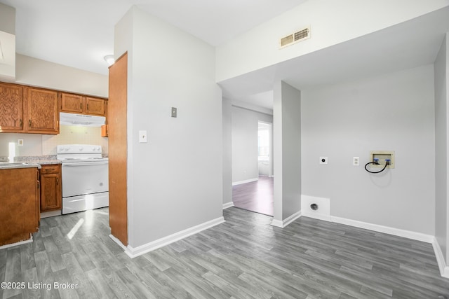 kitchen with visible vents, brown cabinetry, wood finished floors, white electric range, and under cabinet range hood